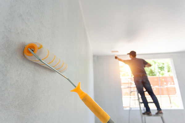Exterior painting on Irvine stucco home with proper ladder setup and surface preparation